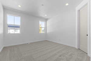 Empty room with light colored carpet and recessed lighting