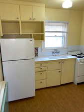 Kitchen with white appliances, tile counters, light wood-type flooring, and white cabinetry