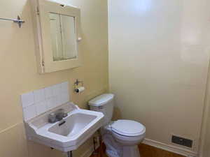 Half bathroom with toilet and wood finished floors