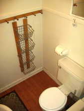 Half bathroom with toilet and wood finished floors