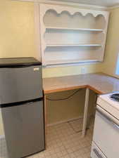 Kitchen featuring built in study area, freestanding refrigerator, light countertops, and white range with electric stovetop