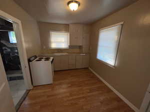 Kitchen with electric range, light countertops, light wood finished floors, and white cabinetry