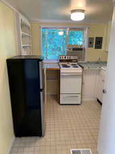 Kitchen with light countertops, white range with electric stovetop, freestanding refrigerator, and electric panel