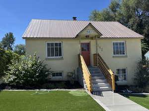 View of front of home featuring stucco siding, a front lawn, and a metal roof