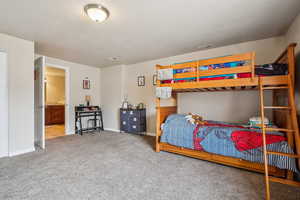 Bedroom with a textured ceiling, light carpet, and connected bathroom