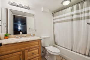 Ensuite bathroom featuring shower / tub combo, vanity, and light tile patterned flooring