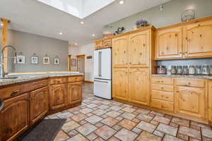 Kitchen with recessed lighting, high end white fridge, a skylight, and light stone counters