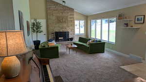 Living area with lofted ceiling, a stone fireplace, carpet flooring, and crown molding