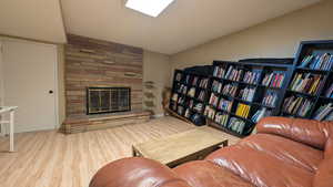 Living area featuring a fireplace, light wood-style floors, and lofted ceiling