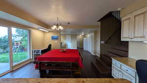 Dining area with dark wood-style flooring, stairs, a textured ceiling, and a chandelier