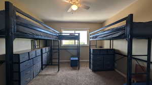 Bedroom featuring dark carpet, ceiling fan, and a textured ceiling