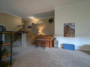 Living area with ornamental molding, light carpet, and stairway
