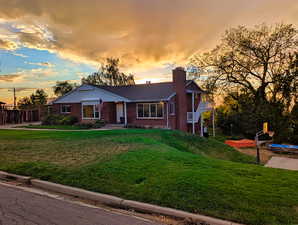 View of front of home featuring a lawn, brick siding, and a chimney