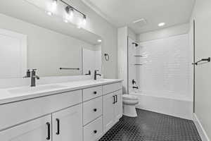 Bathroom with bathtub / shower combination, double vanity, dark tile patterned flooring, and recessed lighting