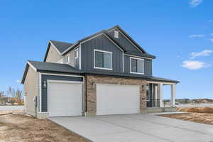 View of front of home with a porch, driveway, brick siding, a shingled roof, and a garage