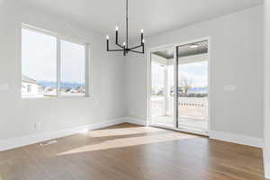 Unfurnished dining area featuring plenty of natural light, a chandelier, and light wood-type flooring