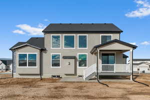 Rear view of house with a patio, stucco siding, and roof with shingles