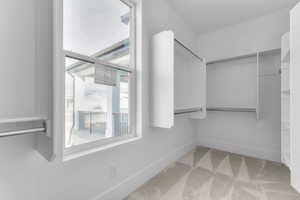 Walk in closet featuring light colored carpet