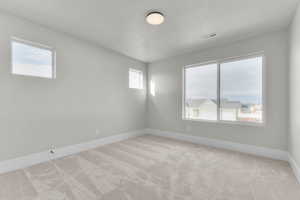 Empty room featuring light carpet and a textured ceiling