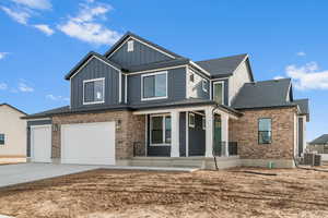 View of front of property featuring a porch, brick siding, driveway, a garage, and board and batten siding