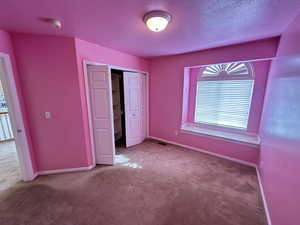 Unfurnished bedroom with carpet, a closet, and a textured ceiling