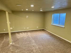 Carpeted empty room featuring a textured ceiling and recessed lighting