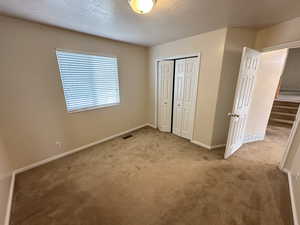 Unfurnished bedroom with a textured ceiling, carpet, and a closet