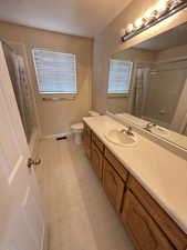 Bathroom with vanity, shower / bath combo with shower curtain, and a textured ceiling