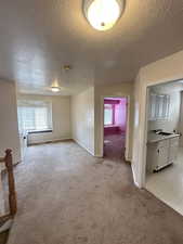 Unfurnished room featuring a textured ceiling and light colored carpet