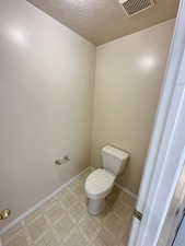 Bathroom with a textured ceiling and light flooring
