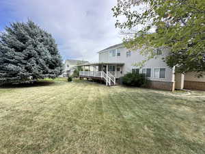 Back of house featuring a lawn, a deck, brick siding, and stairway