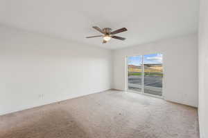 Empty room featuring carpet floors and a ceiling fan