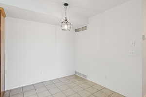 Empty room featuring light tile patterned floors and baseboards