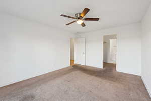 Unfurnished bedroom with carpet floors, ceiling fan, and ensuite bathroom