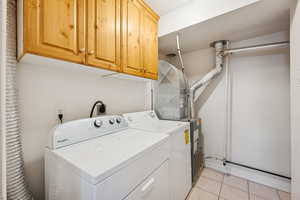 Laundry room with light tile patterned floors, cabinet space, and washing machine and clothes dryer
