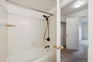 Bathroom featuring carpet flooring and shower / tub combination