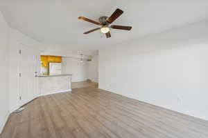 Unfurnished living room featuring light wood-style floors and a ceiling fan