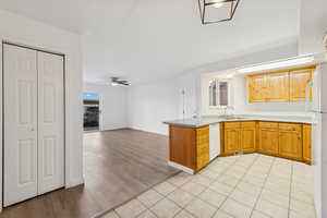 Kitchen with a peninsula, light countertops, open floor plan, white appliances, and light tile patterned floors