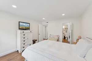 Bedroom featuring dark wood-type flooring, recessed lighting, and connected bathroom