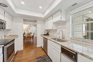 Kitchen featuring decorative backsplash, appliances with stainless steel finishes, white cabinetry, and recessed lighting