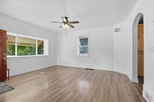 Spare room with light wood finished floors, arched walkways, ceiling fan, and a textured ceiling