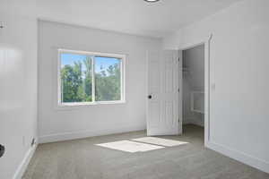 Unfurnished bedroom featuring carpet, a spacious closet, and a textured ceiling