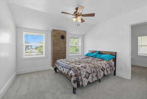 Bedroom featuring light colored carpet, multiple windows, lofted ceiling, and ceiling fan