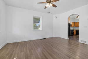 Empty room with ceiling fan, wood finished floors, and arched walkways