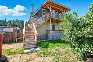 Rear view of property featuring stairway, a chimney, brick siding, a yard, and a wooden deck