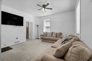 Carpeted living area with a textured ceiling and ceiling fan