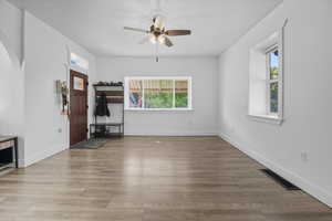 Unfurnished living room with ceiling fan, light wood-style floors, arched walkways, and a textured ceiling