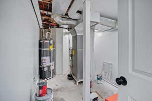 Utility room featuring secured water heater and heating unit