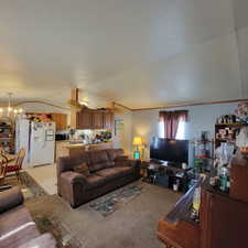 Living room with lofted ceiling, a chandelier, a textured ceiling, and light carpet