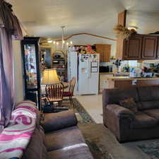 Living room with a chandelier, vaulted ceiling, and a textured ceiling